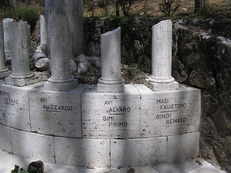 Monumento ai caduti di Scalvaia con colonne e cippi commemorativi in un contesto naturale.