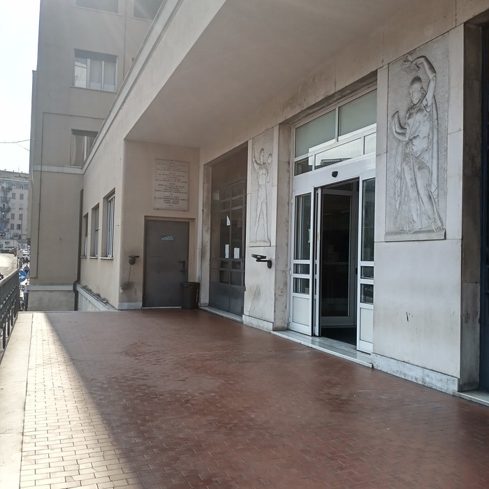 Lapide commemorativa posizionata all'ingresso della Casa dello Studente, con dettagli architettonici.