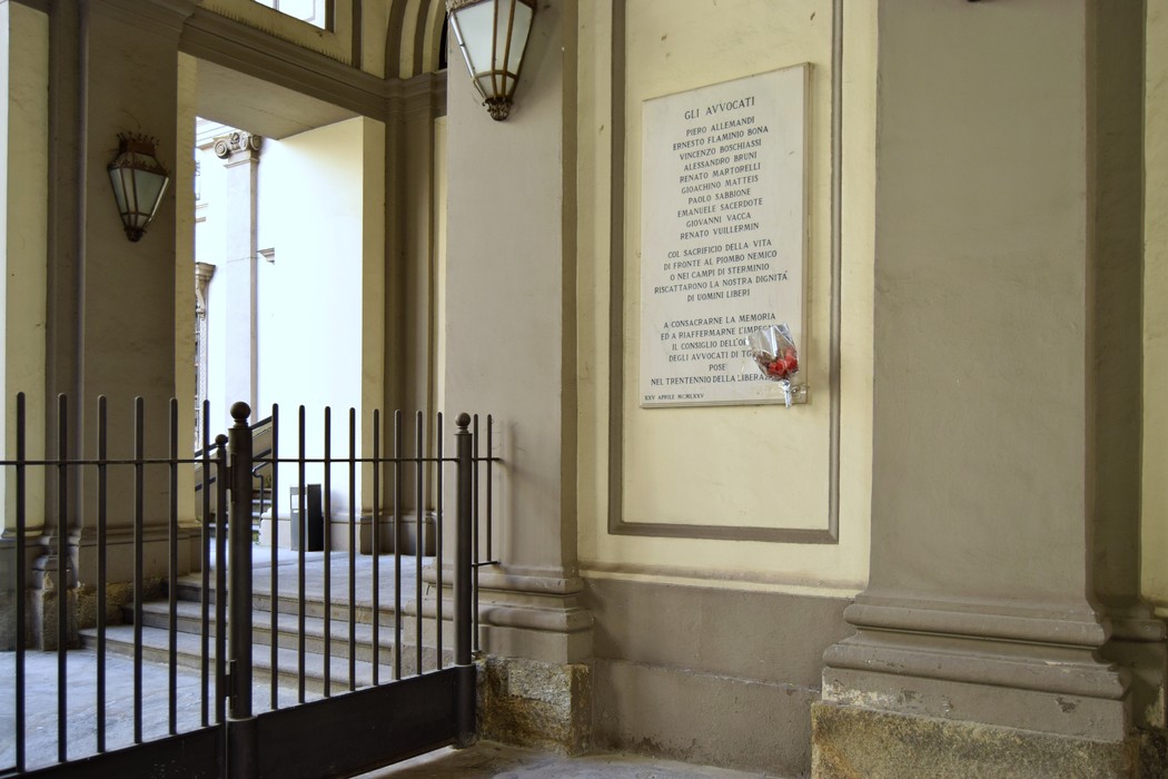 Lapide commemorativa dedicata agli avvocati caduti o internati, posizionata in un ambiente architettonico elegante.