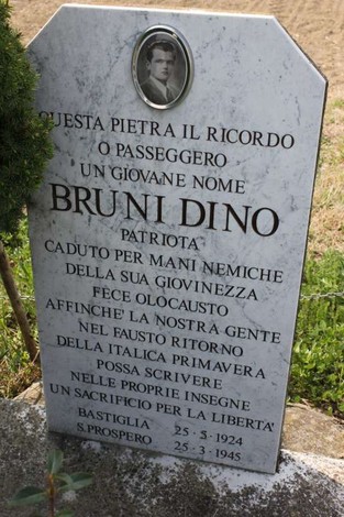 Cippo commemorativo dedicato a Dino Bruni, patriota caduto per la libertà, con foto e iscrizione commemorativa.