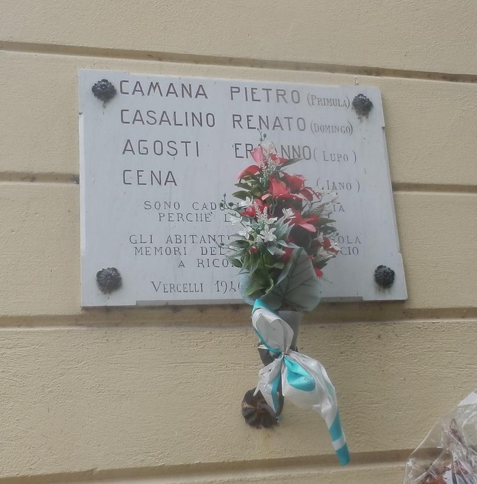 Lapide commemorativa dedicata ai caduti per la libertà, adornata con un mazzo di fiori.