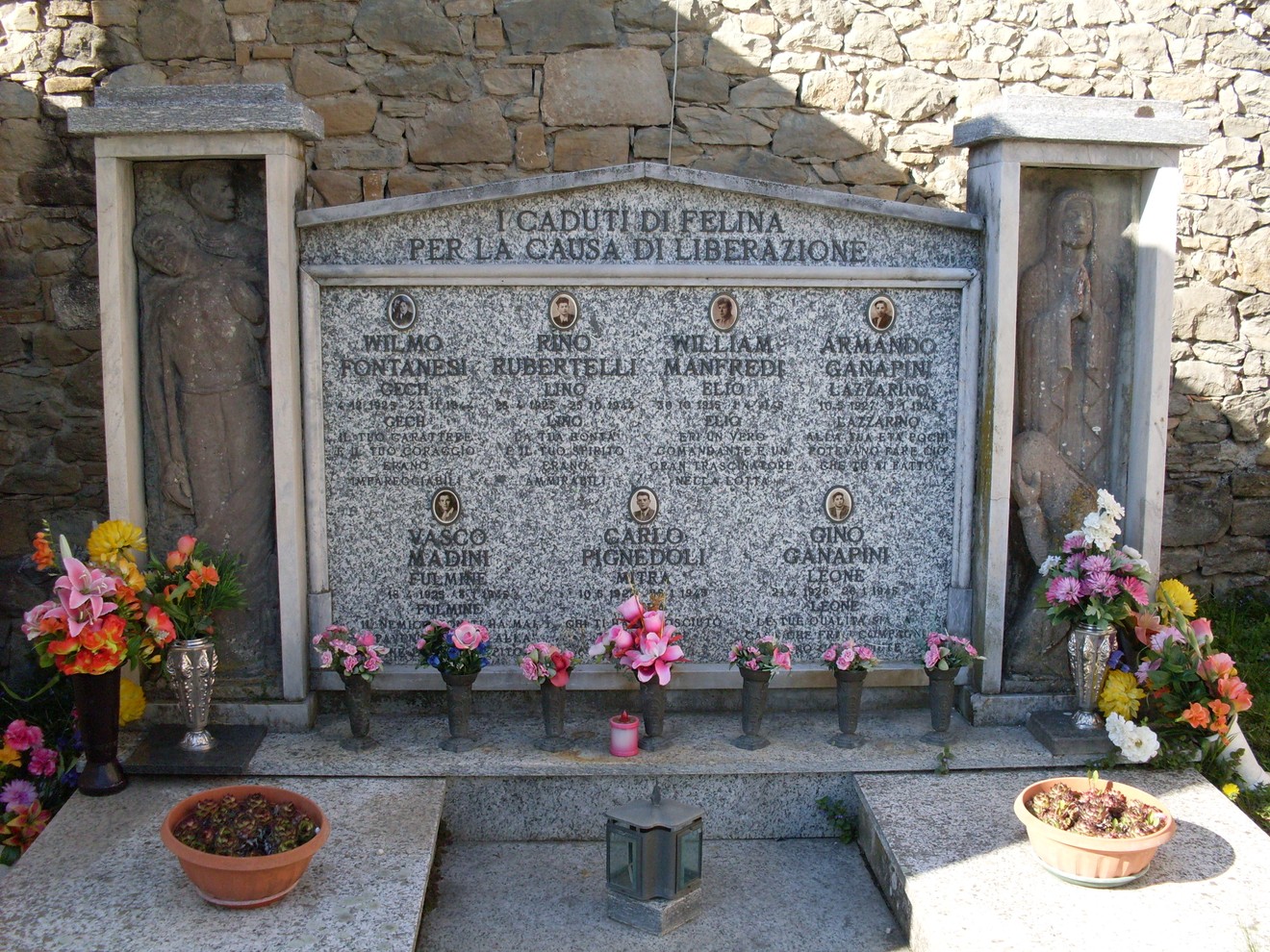 Monumento commemorativo ai caduti partigiani di Felina, decorato con fiori e iscrizioni in memoria dei martiri.