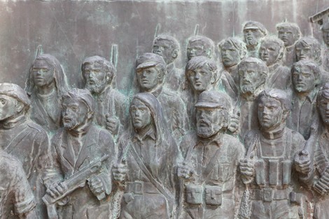 Dettaglio del monumento commemorativo con figure di partigiani scolpite in bronzo, simbolo della Resistenza.