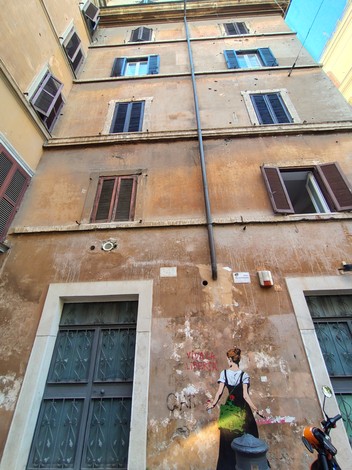 Murale per la Libertà su un edificio storico, con balconi e pareti scrostate. Elementi architettonici caratteristici.