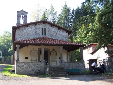 Lapide commemorativa del ventennale dell'eccidio del Castagno presso una chiesa immersa nella natura.