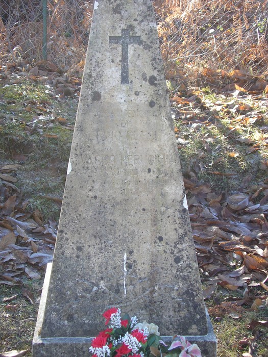 Cippo commemorativo dedicato a Chesi e Perugini, con decorazioni floreali e croce in cima.