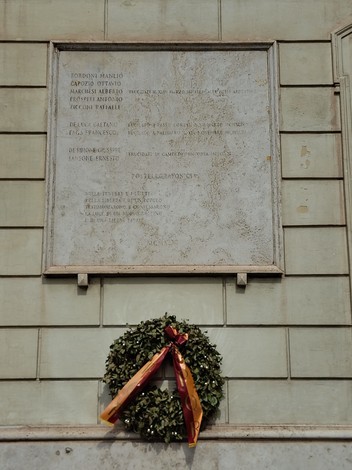 Lapide commemorativa dedicata ai postelegrafonici caduti per la Libertà, adornata con un fiocco e una corona di alloro.