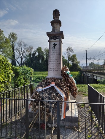 Monumento ai dieci martiri, con decorazioni floreali e un'atmosfera di commemorazione in un contesto naturale.