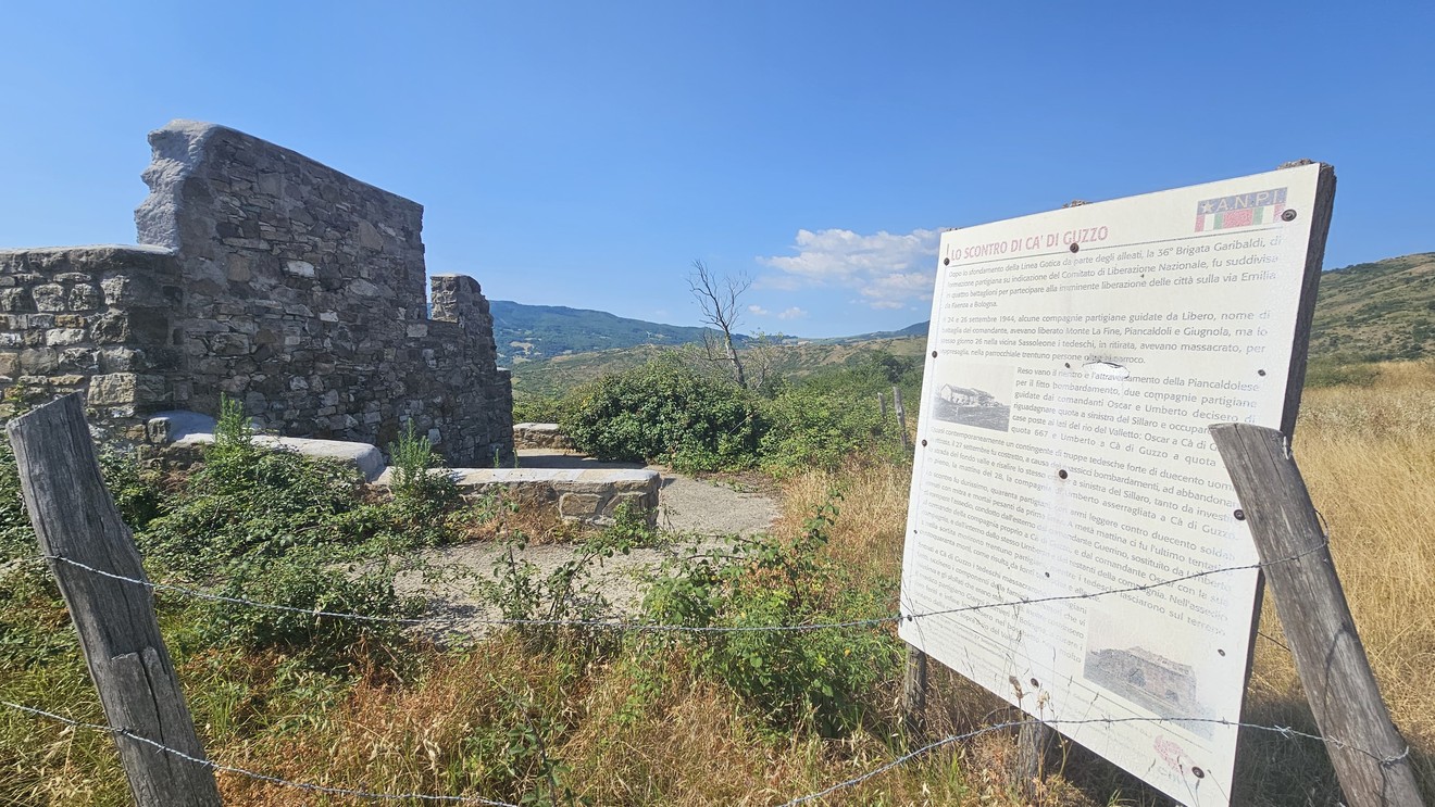 Rovine di Ca' di Guzzo immerse nella natura, con un cartello informativo nelle vicinanze.