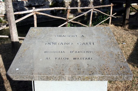 Cippo commemorativo dedicato a Doriano Galli, medaglia d'argento al valor militare, situato in un'area verde.