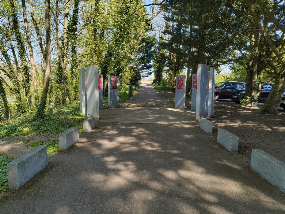 Il Memoriale del Gruppo Manouchian è circondato da alberi, con un viale che porta a una zona aperta.