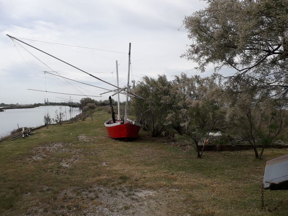 Isola degli Spinaroni: paesaggio caratterizzato da barche e vegetazione tipica della laguna.