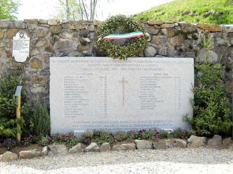 Lapide commemorativa ai caduti partigiani, decorata con una corona e un nastro tricolore.