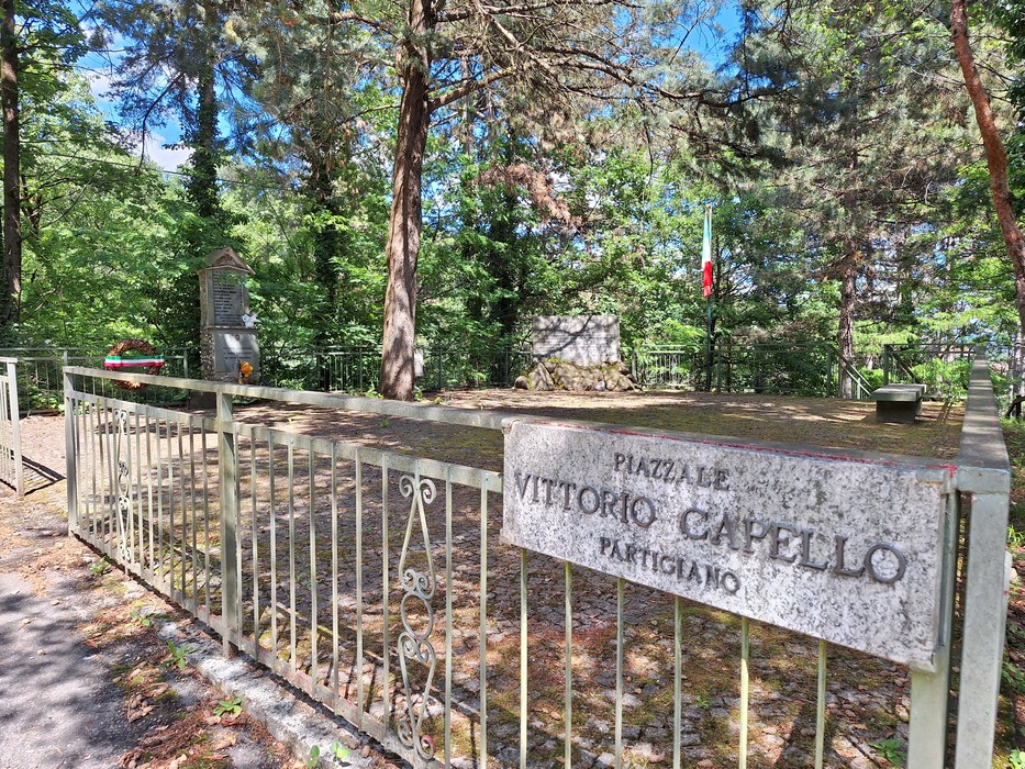 Monumento ai giovani partigiani, circondato da alberi e con una recinzione in metallo. Un luogo di memoria e rispetto.