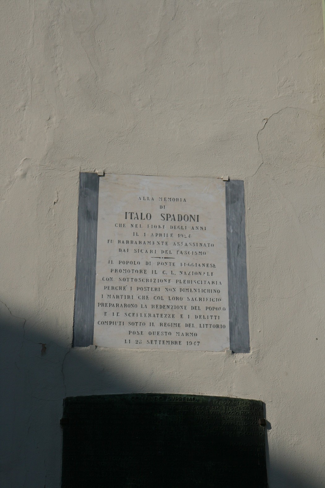 Lapide in memoria di Italo Spadoni, commemorativa e storica, affissa su un muro.