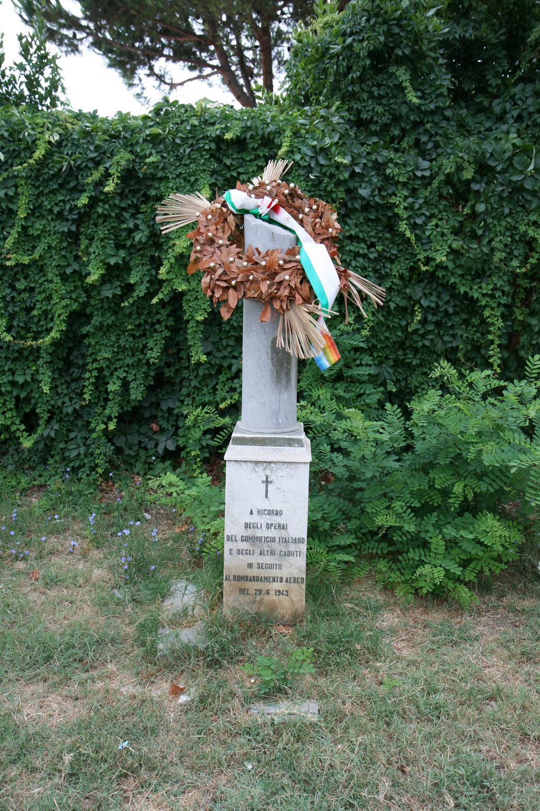 Cippo commemorativo con corona di alloro in onore del Gommificio Italiano, immerso nella natura.