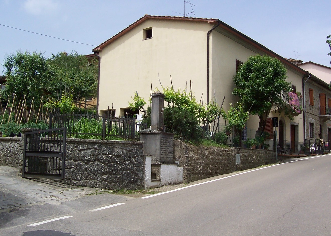 Monumento a Ceccaroni, situato in un contesto rurale con giardini e case tradizionali.