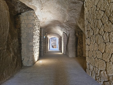 Veduta interna delle "Fosse Ardeatine", con muri in pietra e un corridoio che si estende verso il fondo.