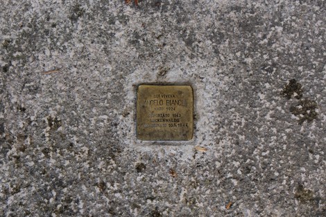 Pietra d'inciampo dedicata a Angelo Bianchi, commemorazione di una vita, su pavimentazione grigia.