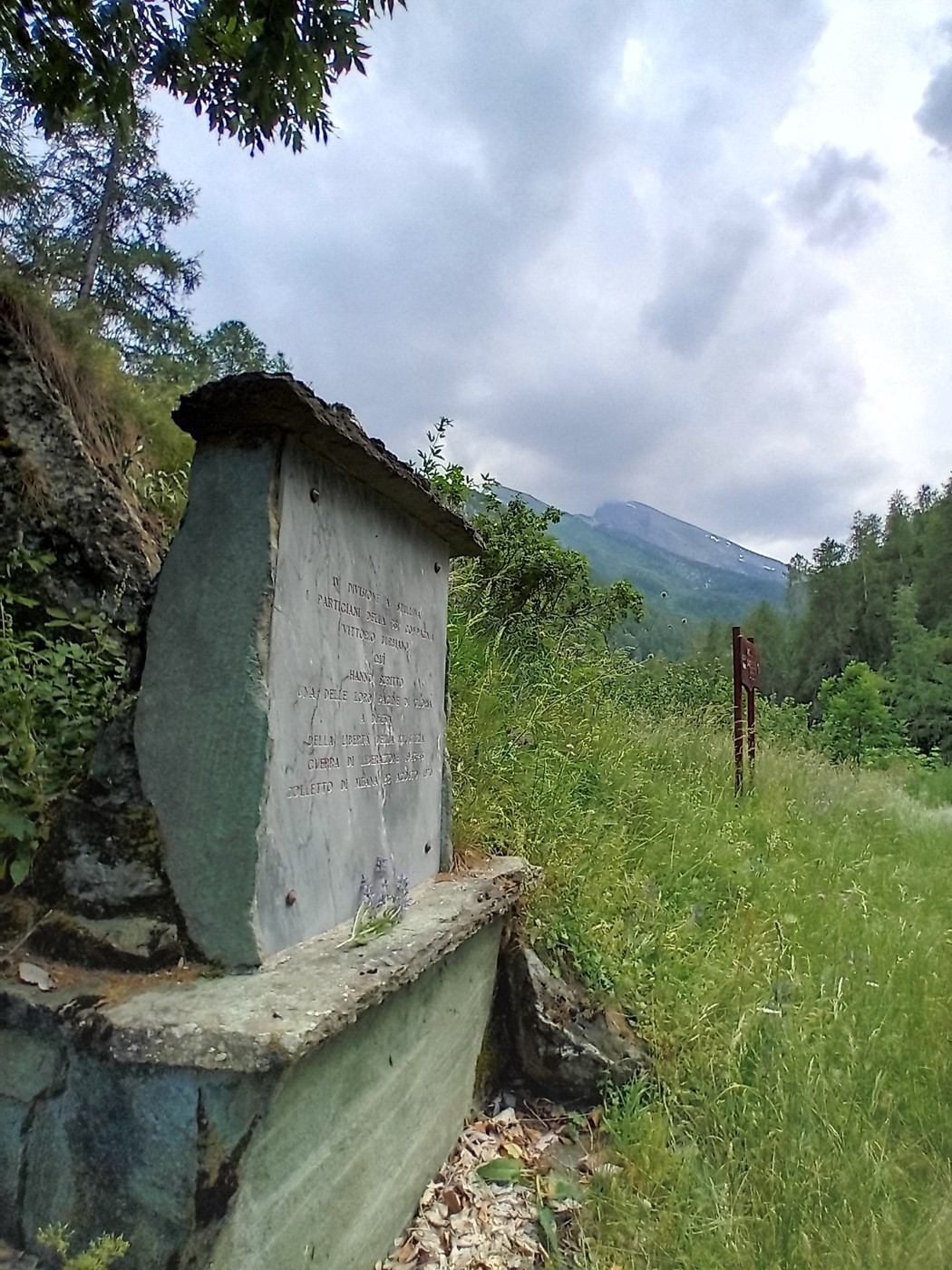 Monumento ai partigiani della Divisione Stellina, circondato da natura e montagne, in un contesto storico significativo.
