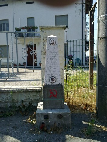 Cippo commemorativo dedicato a Folloni e Pagliotto, situato in un contesto urbano.