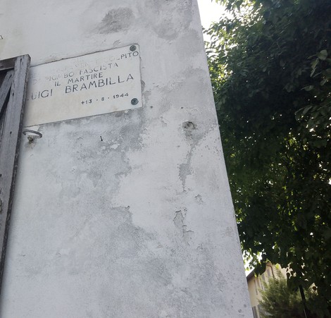 Lapide commemorativa dedicata a Luigi Brambilla, martire della Resistenza, in un ambiente verde.