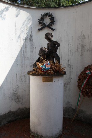 Monumento ai Caduti con statua commemorativa e decorazioni floreali, immerso in un'atmosfera di rispetto e memoria.
