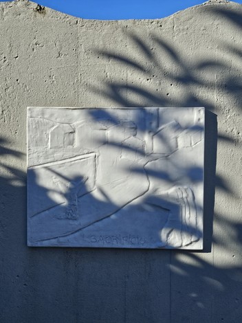 Monumento alla Resistenza con rilievo su parete, dettagli artistici evidenti e suggestive ombre.