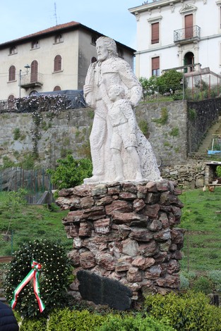 Monumento alla Resistenza che rappresenta una figura adulta con un bambino, eretto su una base in pietra.