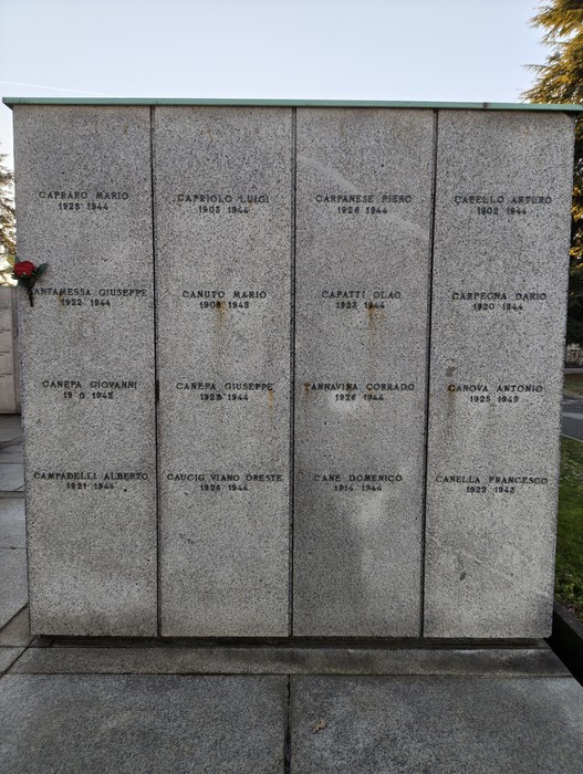 Monumento commemorativo nel Campo della Gloria con nomi e date di caduti in guerra. Rose commemorative adornano la superficie.