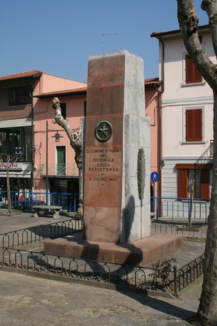 Monumento del decennale dedicato alla Resistenza, situato in un'area urbana con alberi e edifici.