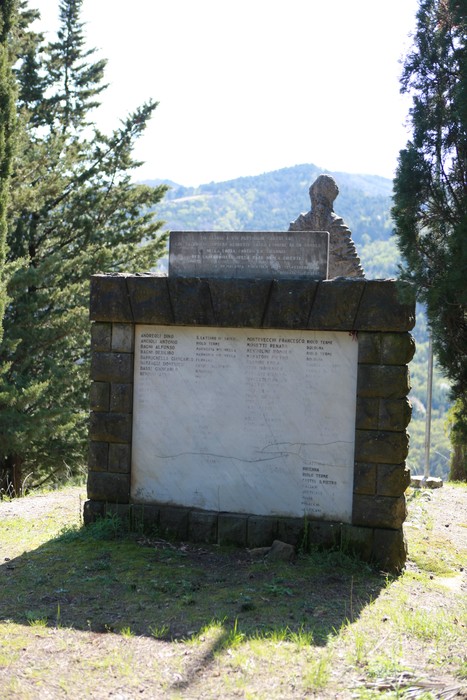 Monumento ai caduti di Purocielo, con base in pietra e iscrizioni commemorative, immerso nella natura circostante.