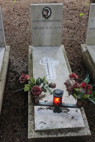 Tomba con croce e decorazioni floreali, lampada accesa e pietra commemorativa di Aimone Martini.