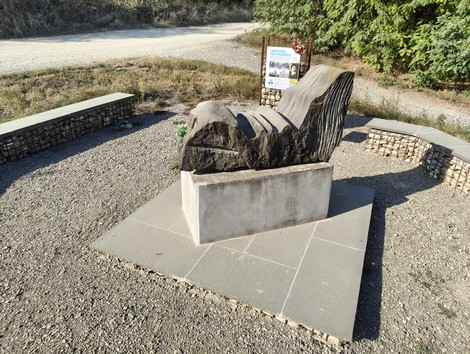 Monumento ai Martiri del Panaro, scultura su base di pietra con panchine intorno, immerso nella natura.