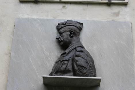 Lapide commemorativa con busto in bronzo di un ufficiale, incastonata in una parete di pietra.