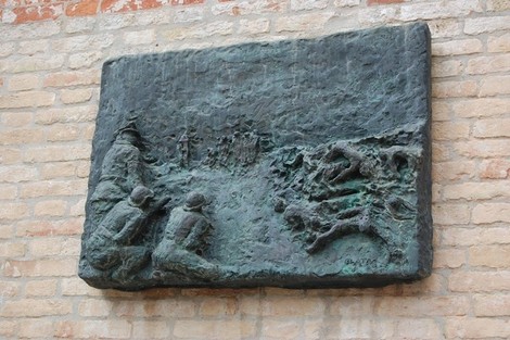 Rilievo bronzeo che rappresenta la sofferenza durante l'Olocausto, con figure umane e simboli di lutto.