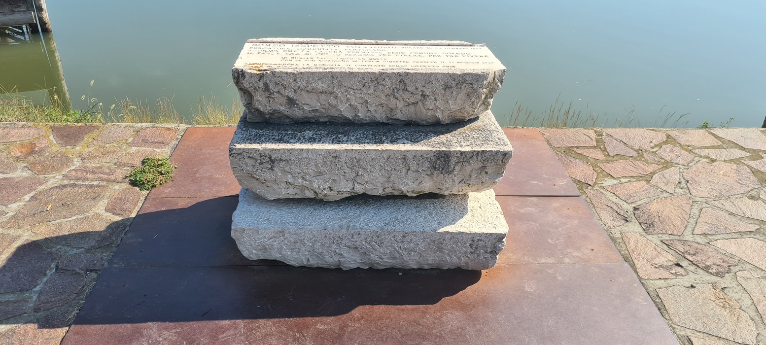 Monumento a Isepetto, composto da tre massi sovrapposti con vista su un corpo d'acqua.