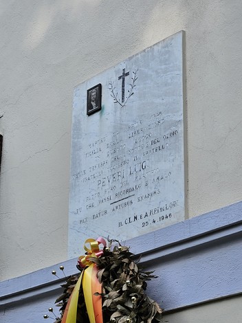 Lapide commemorativa nel comune di Peveri, con corona di fiori e simboli religiosi.