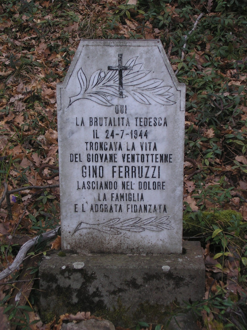 Cippo commemorativo di Gino Ferruzzi, vittima della brutalità tedesca nel 1944, circondato dalla natura.