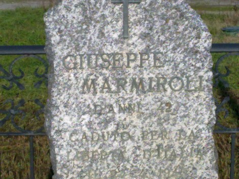 Cippo commemorativo in memoria di Giuseppe Marmiroli, situato in un contesto naturale.