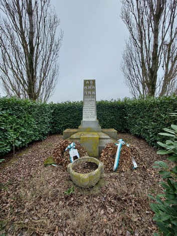 Monumento commemorativo dedicato alle vittime dell'eccidio del Palazzone, circondato da siepi e decorato con corone.