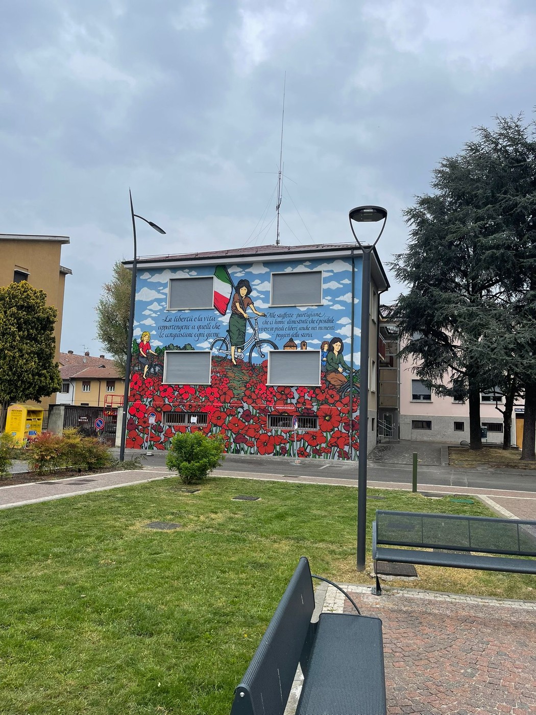 Murale commemorativo delle staffette partigiane, con fiori rossi e simboli della resistenza italiana.