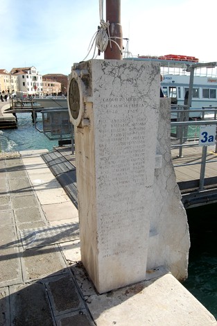Cippo commemorativo dedicato ai dipendenti Acnil caduti, situato sul molo, con vista sul canale.