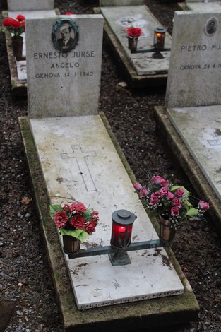 Tombe con fiori e lumini, in memoria dei caduti per la Libertà, immerse in un'atmosfera di rispetto e commemorazione.