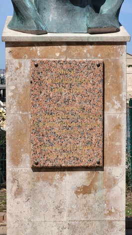 Giardino Missak Manouchian con monumento e placca commemorativa su sfondo verde e cielo sereno.