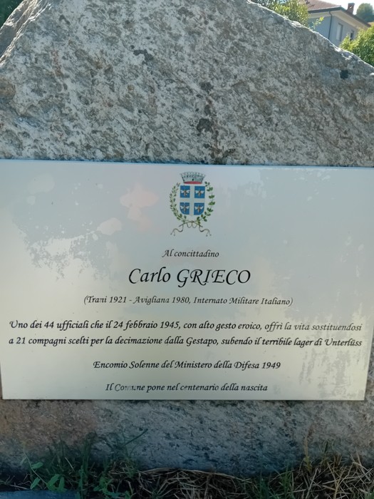 Cippo in pietra con targa metallica e stemma, incisa con dedica a Carlo Grieco.