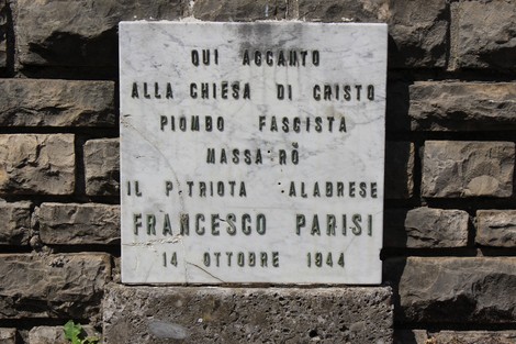 Lapide commemorativa in marmo dedicata a Francesco Parisi, situata vicino a una chiesa.