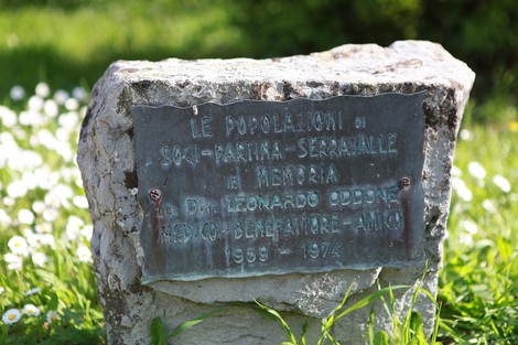 Monumento ai caduti di Soci, con targa commemorativa in un contesto naturale fiorito.