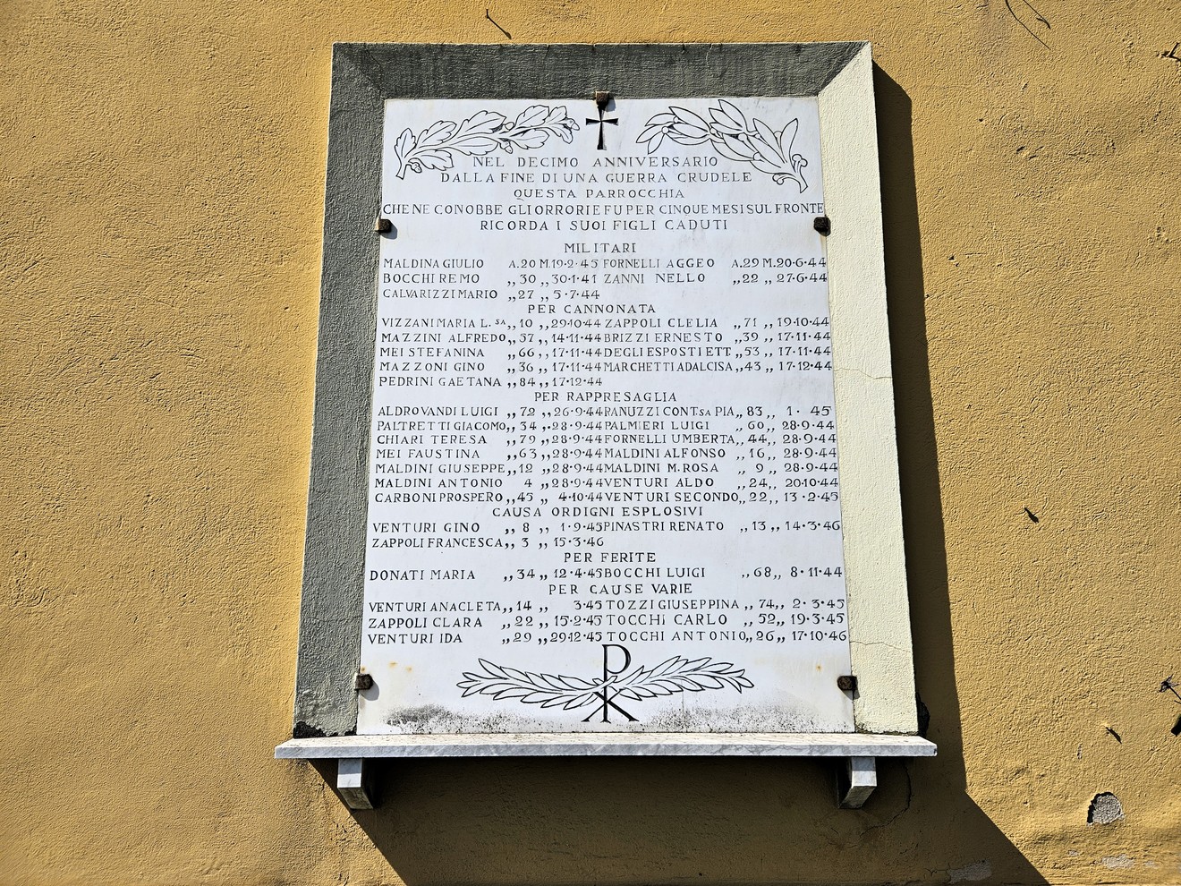 Lapide marmorea con lunga iscrizione e cornice decorata, affissa su parete esterna color ocra.