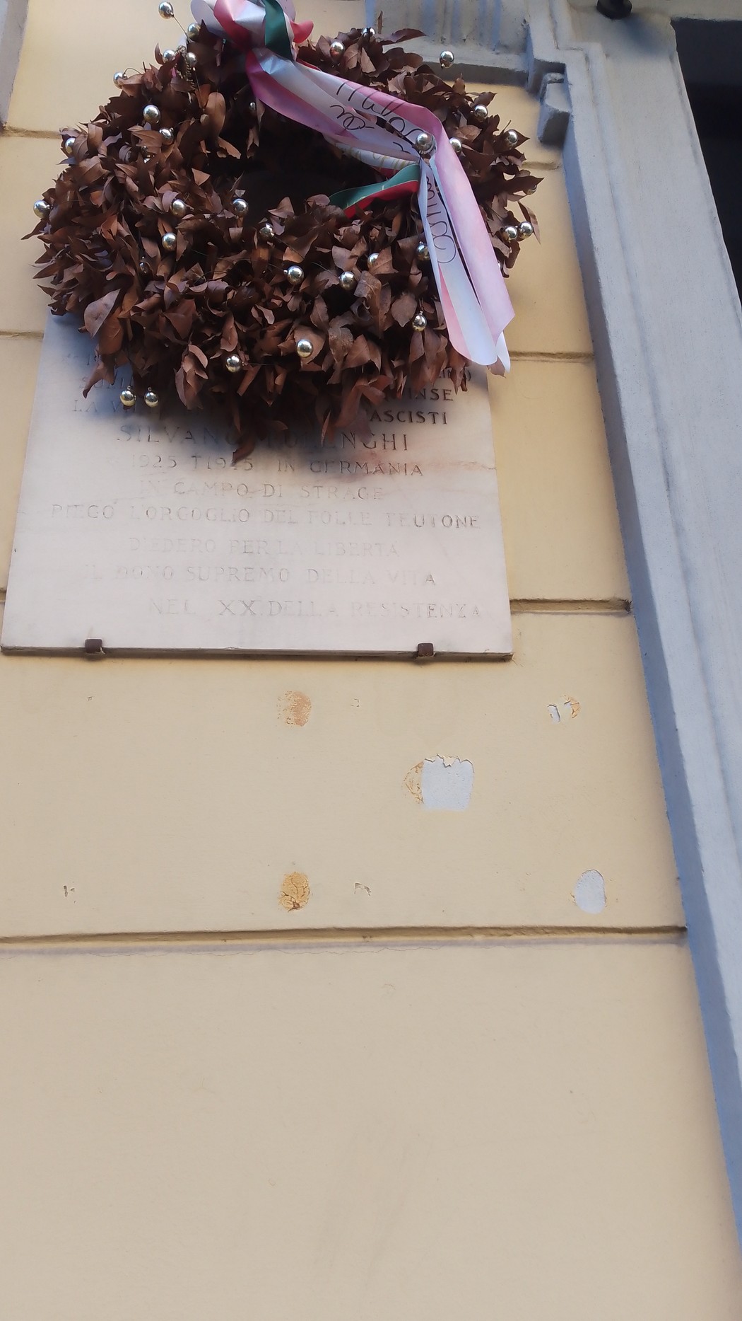 Lapide commemorativa con corona d'alloro su muro, in memoria di Gabellini e Polenghi.